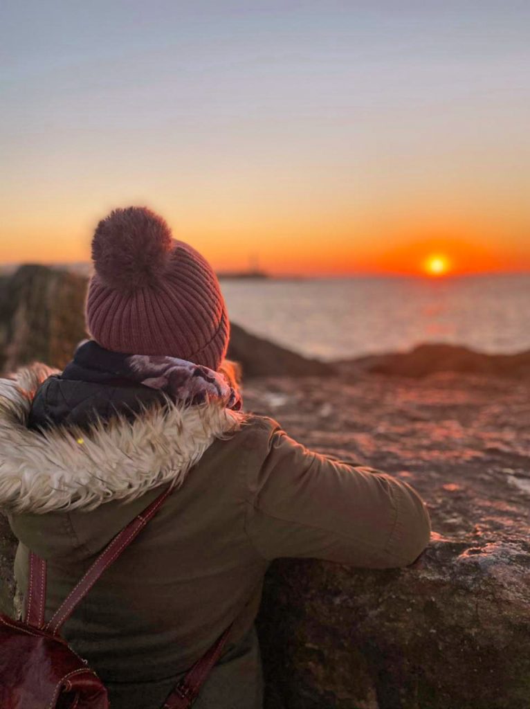Frau schaut auf den Sonnenuntergang über dem Meer