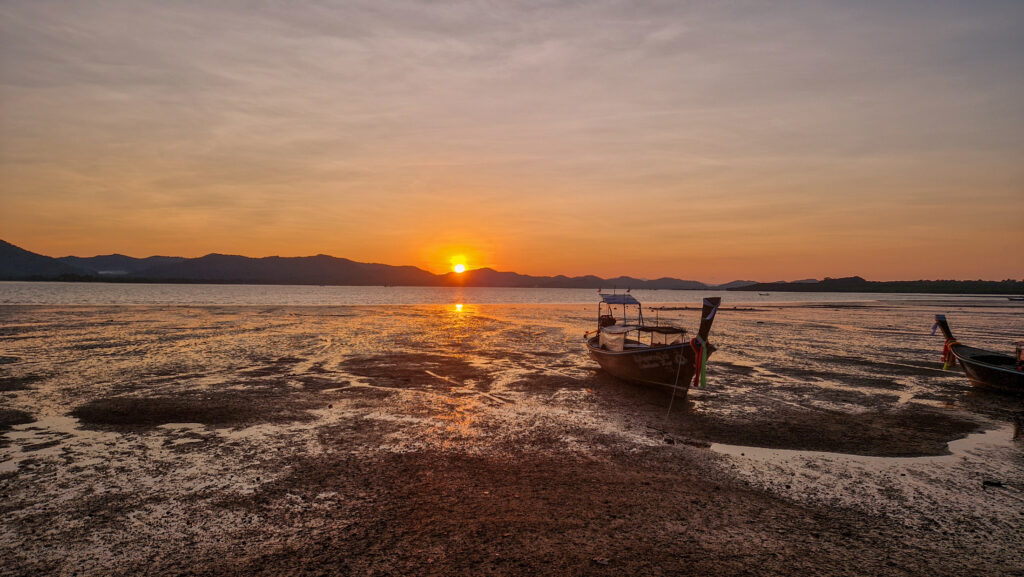 Atemberaubender Sonnenuntergang über dem Meer auf Koh Yao Noi mit Longtailbooten
